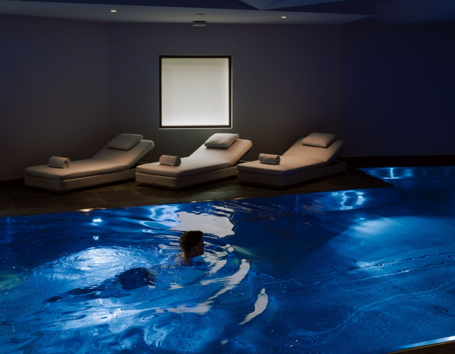 Man swimming in the blue pool at THE SPA in St. Moritz.