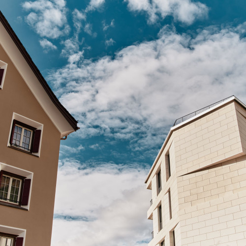 Detailed picture of two buildings with clouds and blue sky in the background 