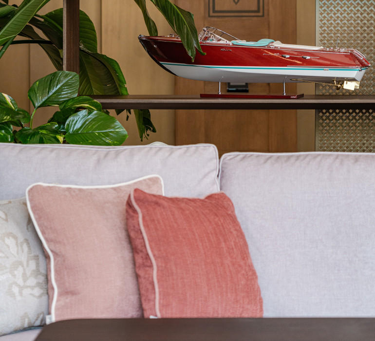 Close-up of a grey couch with light pink pillows and a plant