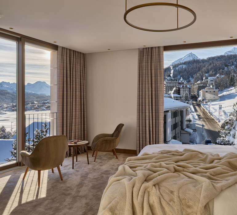 Cozy hotel room with a furry blanket, double bed and two seats directed to the panorama view