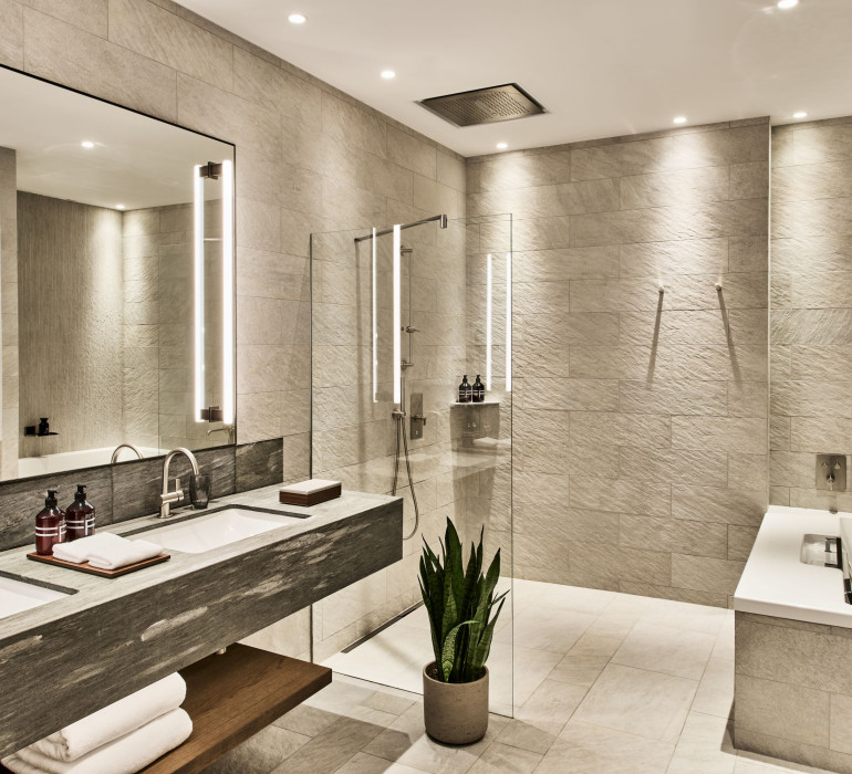 Modern bathroom with a walk-in shower, a large stone sink and light-up mirrors