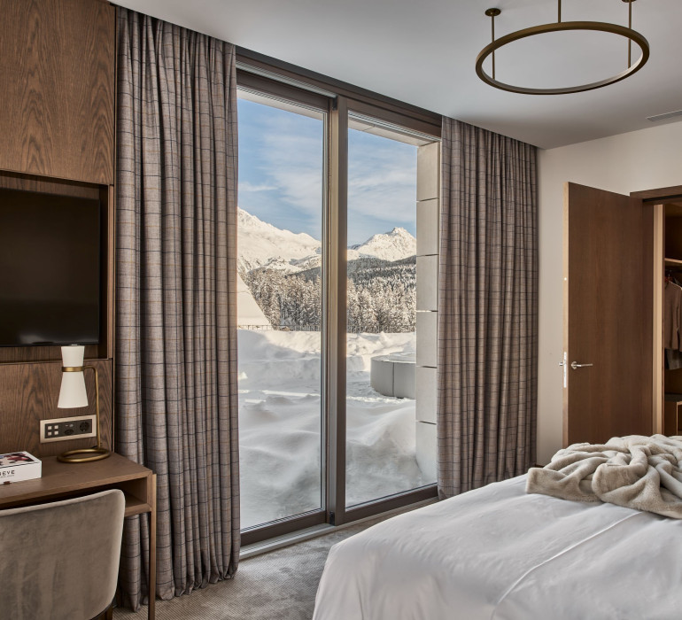 Cozy hotel bed in St. Moritz with lounge area infront of the panoramic mountain view