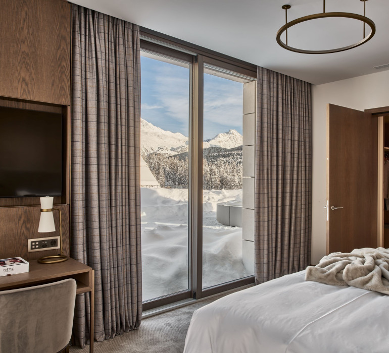 Hotel room with double bed and a snowy terrace with mountain view