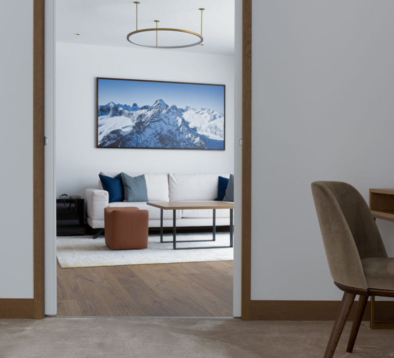 Hotel suite in St. Moritz with a door, lounge area with cozy furniture and a painting of mountains