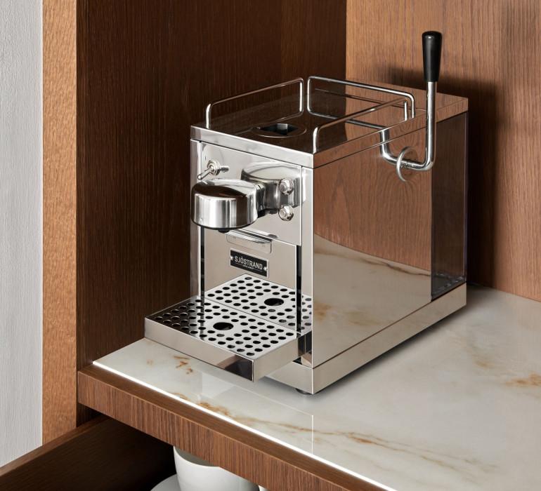 Small coffee machine on a marble plate in a brown cupboard