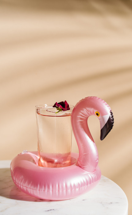 A flamingo cup holder with a transparent cocktail