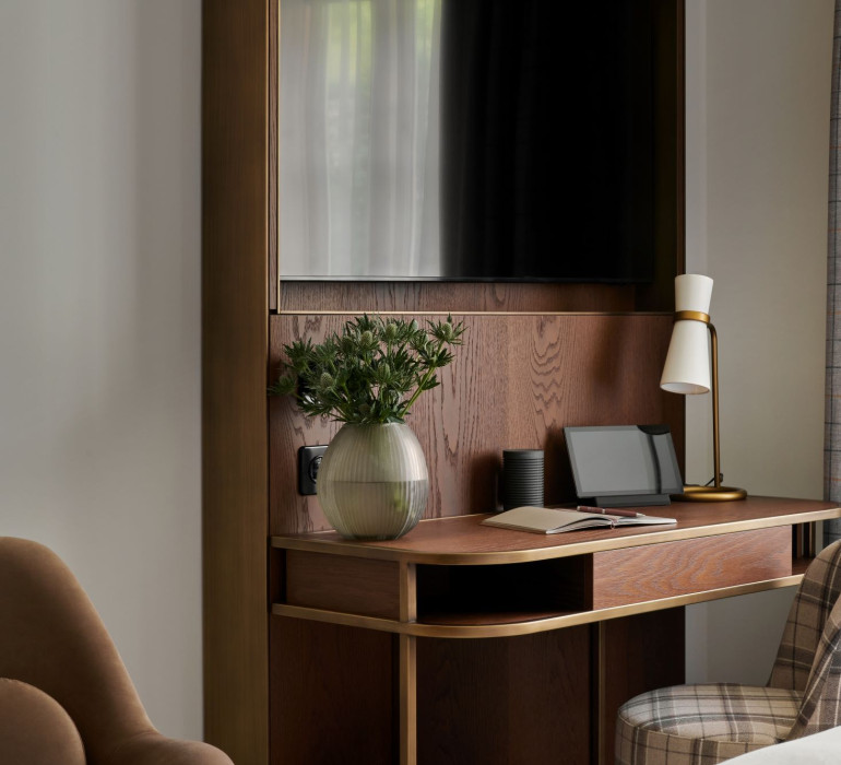 Details of a hotel room with a wooden desk with plants, tablet and a lamp