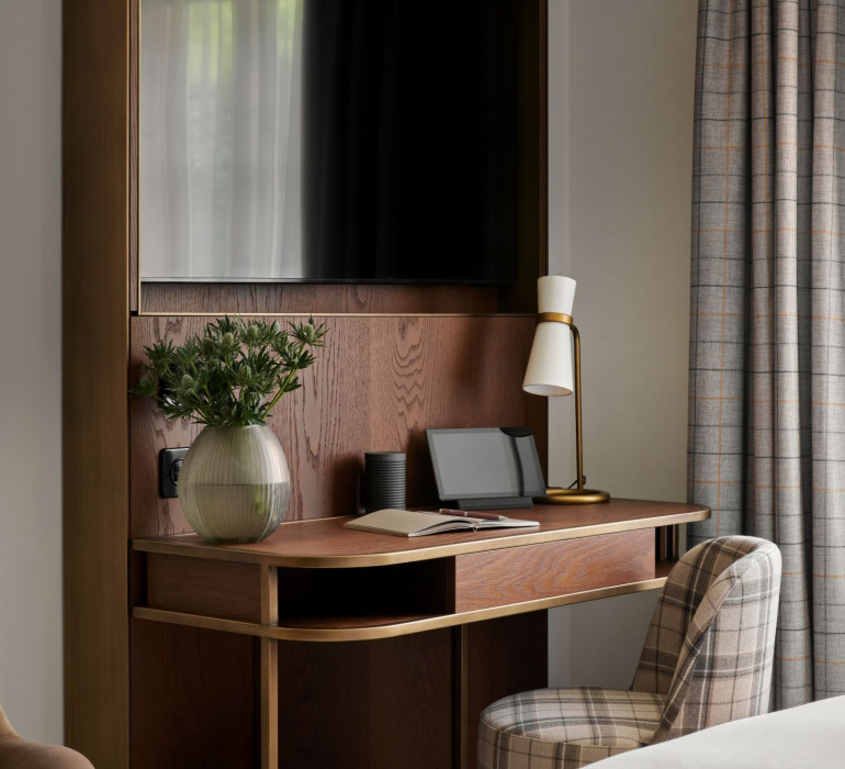 Details of dark wood furniture with books and a tablet in an elegant hotel room