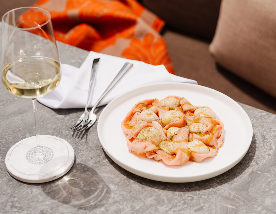 Italian lunch on a white plate with a glass of white wine next to it