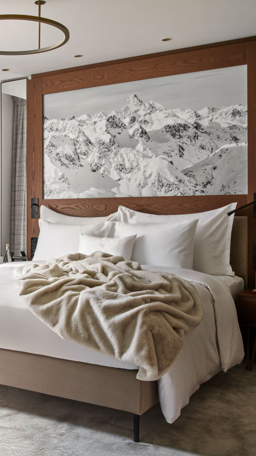 Cozy hotel bed with a mountain painting over the head part