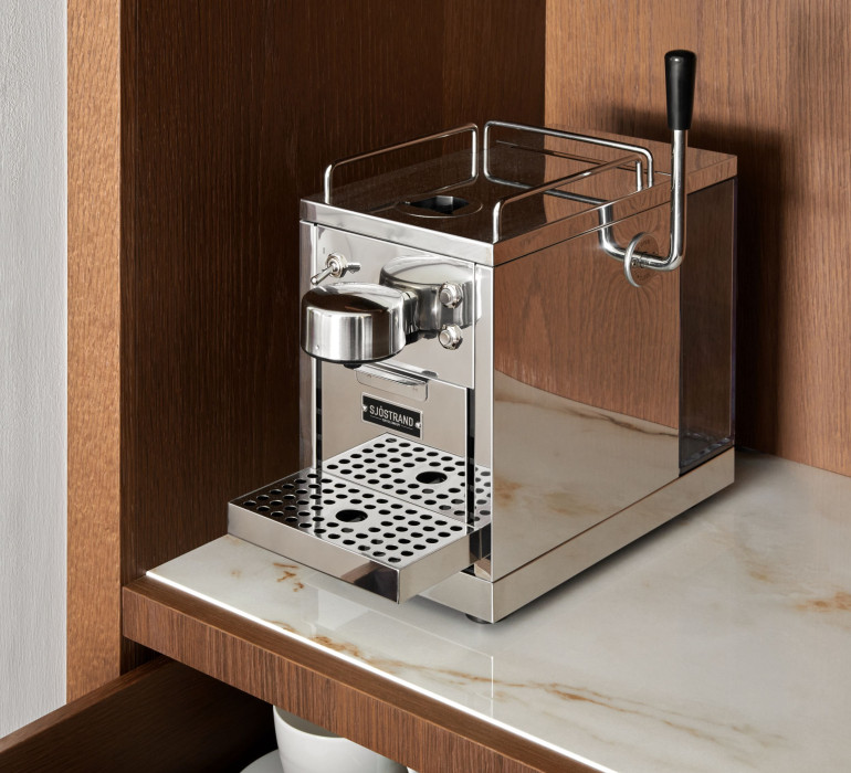 Details of a silver metal coffee machine on a marble plate in a shelf