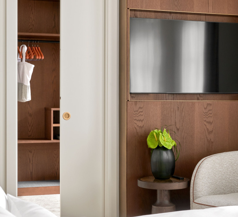 Hotel suite with wooden walls, a built-in TV and an empty dressing room