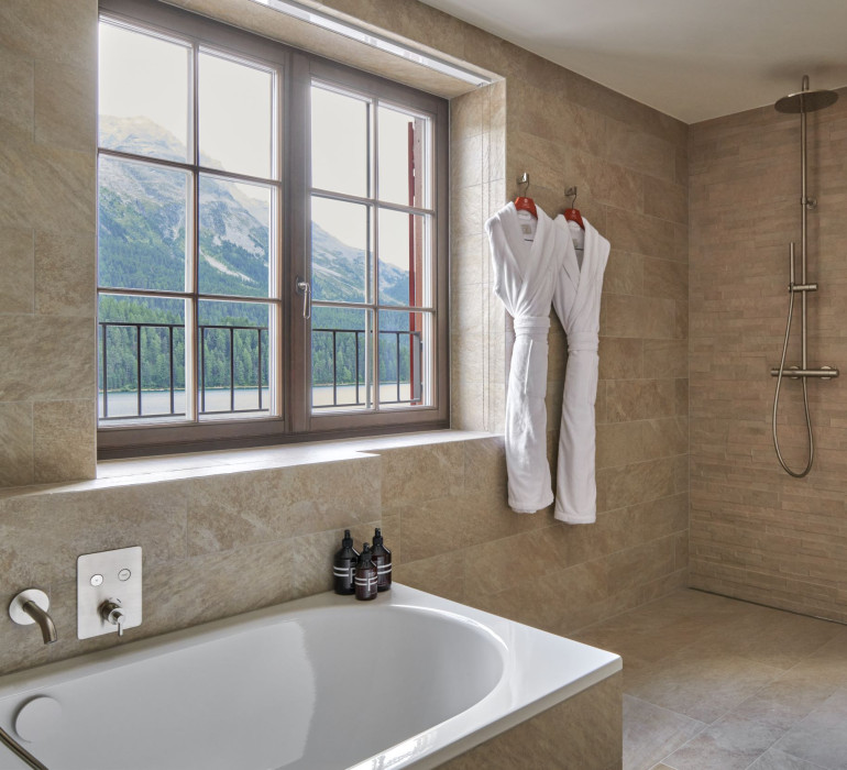 Light bathroom with an open shower, a bath tub and large windows with a mountain view