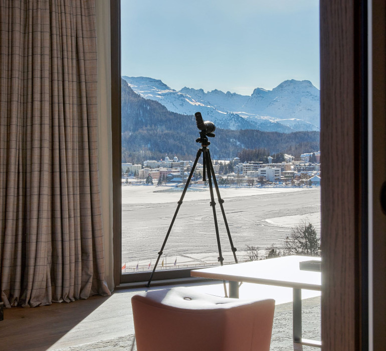 A camera is placed infront of a large window with a panorama view at the mountains