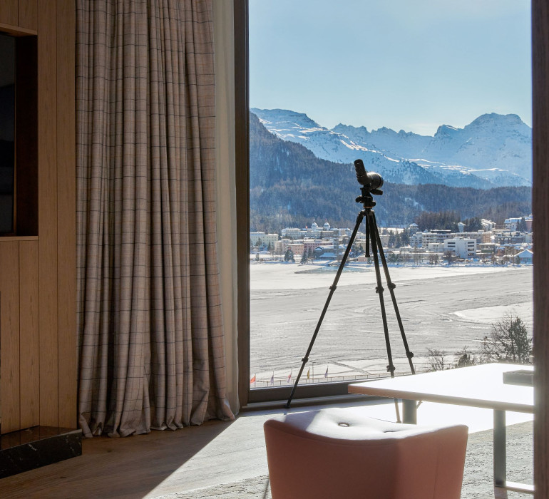 A camera is set up infront of a large window with a panorama view at the alpine mountains