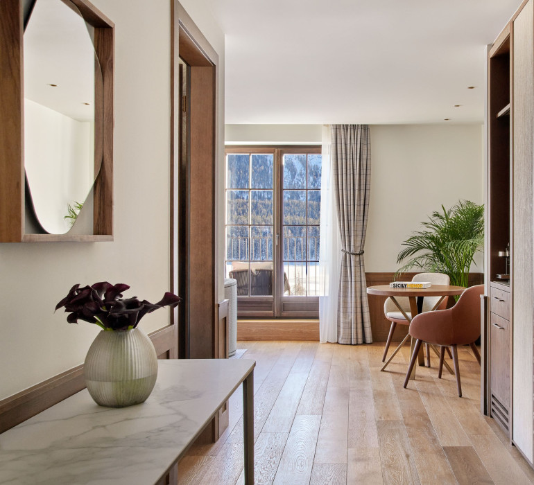 Hallway of a bright suite with a marble table and wooden door frames