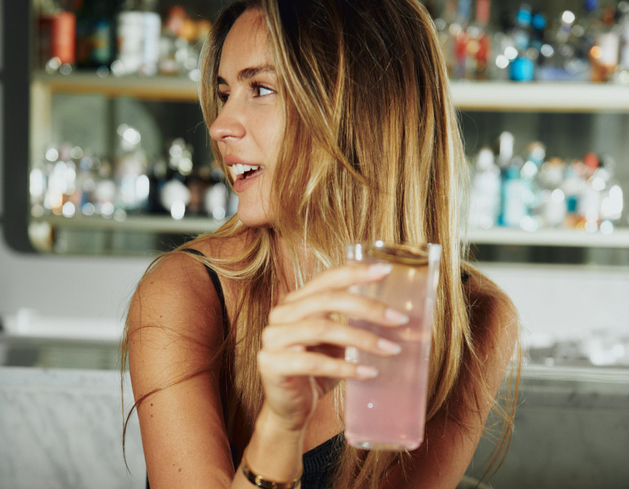 A woman is holding two drinks in front of her eyes at the 5 star hotel st moritz