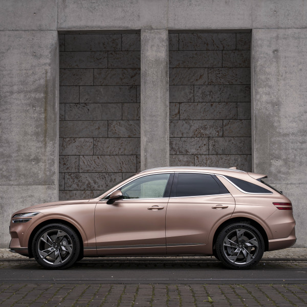 A rose golden car is parked in front of a grey wall at the luxury hotel st moritz