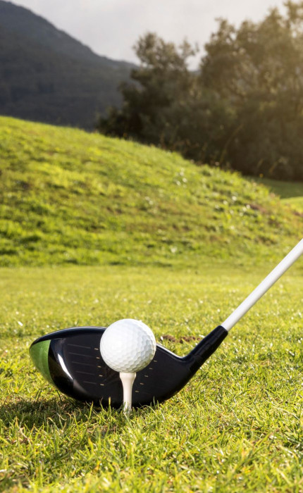 Details of a golf stick hitting a golf ball on a green landscape